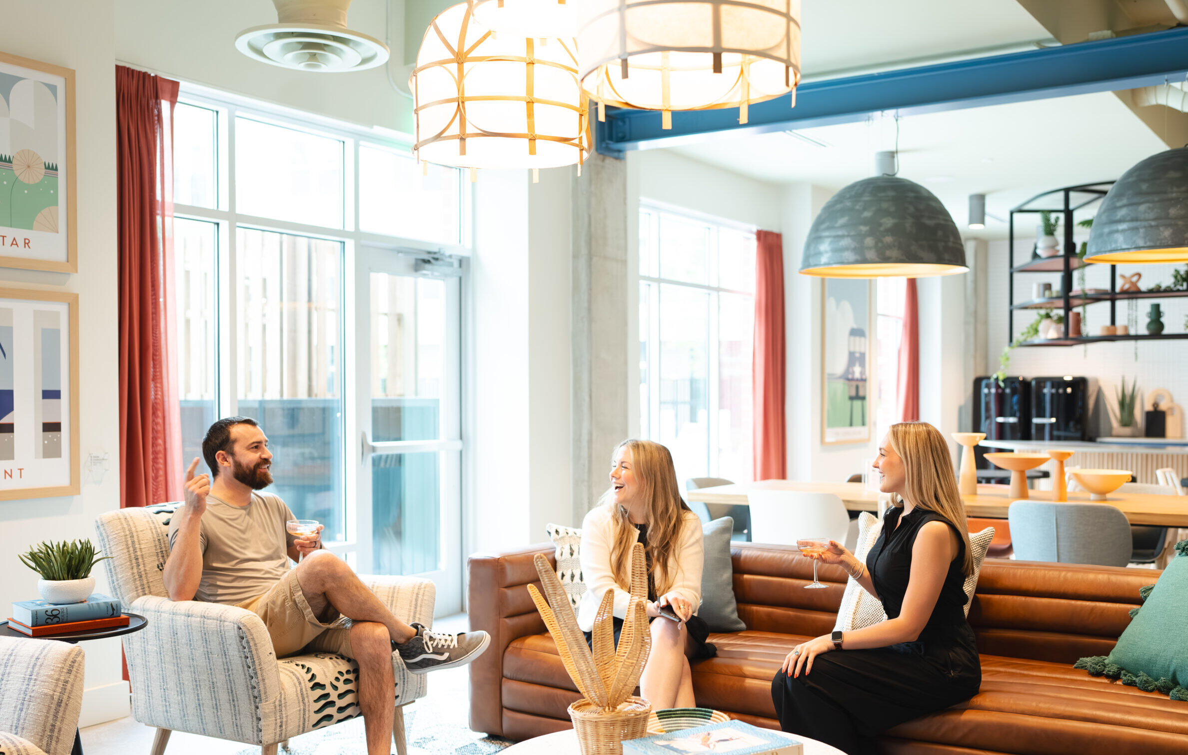 clubroom image with three people, and one person is holding a beverage in conversation.